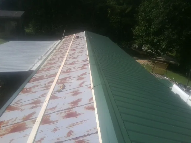 Old rusted panels beside newly installed green metal roofing — Wind Damage Roof Repair by Roofing Brothers in Myerstown