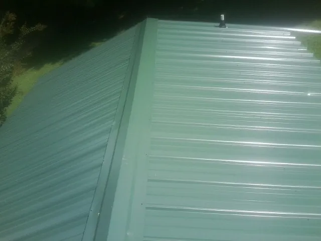 New green metal panels meeting at the ridge of a roof — Flat Roof Repair work by our crew in Myerstown