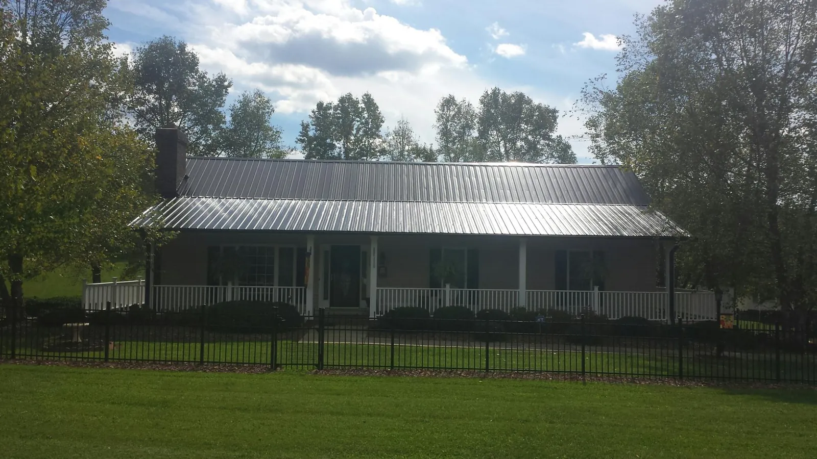Gray metal roof on a brick ranch with a full width front porch — Gutter Guard Installation work by our crew in Myerstown