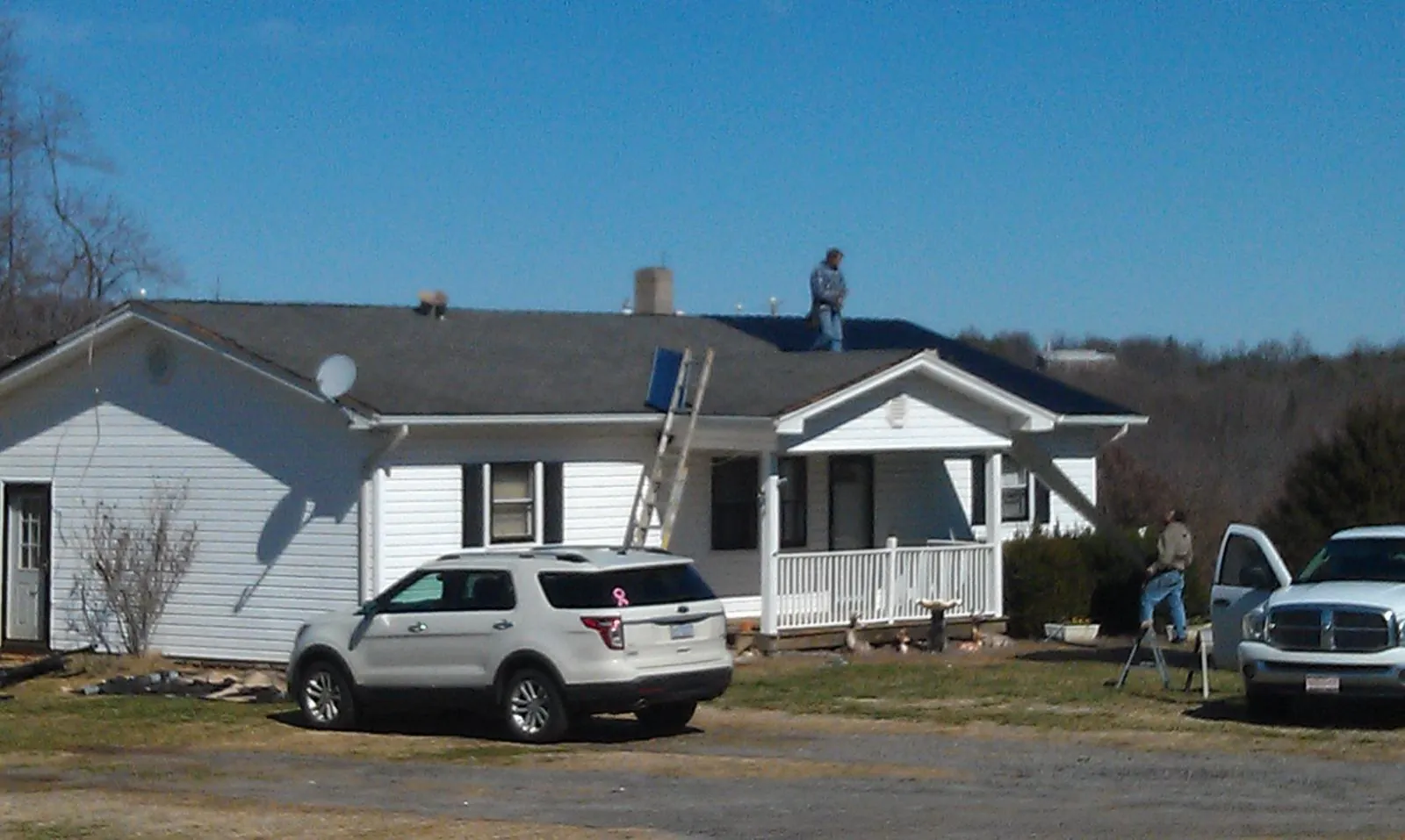 Roofers stripping shingles from a white ranch house roof in Myerstown