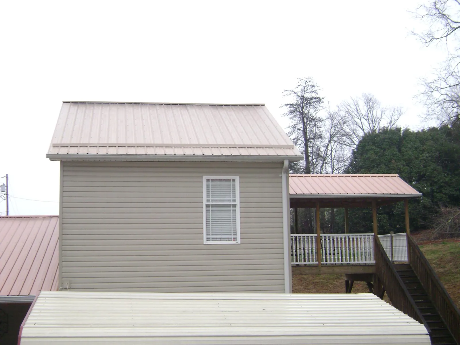 Tan metal roofs on a two story addition and attached porch, from a Roof Replacement job in Myerstown