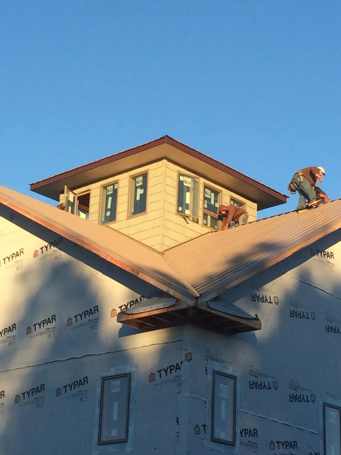 Roofers working around a rooftop cupola on a new metal roof at sunset — Roof Waterproofing in Myerstown by Roofing Brothers